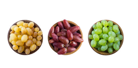 Grapes in a wooden bowl isolated on white background. Yellow, pink and green grapes on white background. Vegetarian or healthy eating. Top view.