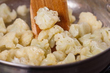 young woman in a gray apron roasts cauliflower broccoli