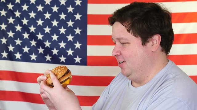 Man with a hamburger with an American flag background. Big guy wants fast food