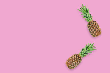 Two fresh whole pineapples with green leaves lying on pink table on kitchen. Top view. Cooking concept. Copy space for your text