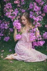 Outdoor fashion photo of beautiful young woman surrounded by flowers. Spring blossom