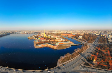 Beautifull aerial view of the Petropavlovsky fortress in sunny spring day. Golden tall spire of famous Peter and Paul Cathedral on the blue sky background. Historical centre of St. Petersburg, Russia.