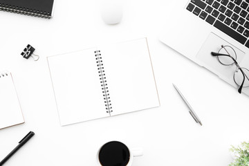 White office desk table with two blank pages of notebook with supplies. Top view with copy space, flat lay.