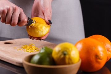 young woman in a gray aprons cuts lemon zest