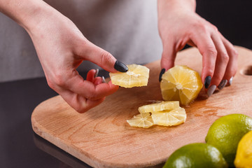 young woman in a gray aprons cut lemon