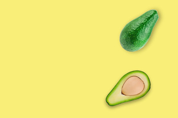 Fresh whole and half of organic avocado with kernel on yellow table in kitchen or market. Top view. Cooking concept. Copy space for your text