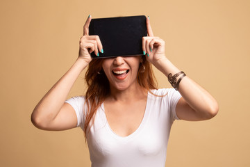 Young Asian woman with a computer tablet over her face.