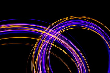 Long exposure, light painting photography.  Vibrant loops and streaks of neon purple and metallic gold color against a black background.