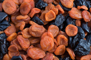 Dried apricots and prunes lie on the table in daylight Dried fruits-dried apricots and prunes of bright saturated colors are delicious in one plane 