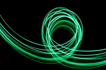 Long exposure, light painting photography.  Vibrant loops of neon green color, abstract design, against a black background.