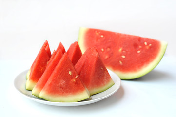 Red watermelon slices on white plate over white background, selective focus