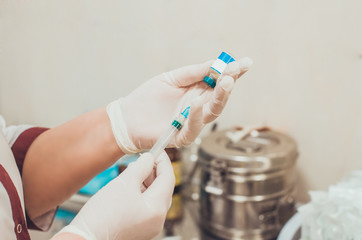 Nurse holding a medical syringe and putting medicine inside it. Injection preparation in hospital.