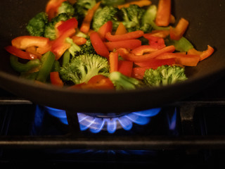 colorful vegetables cooking on stovetop wtih flame