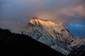 Chenadorje, holy snow mountain in Daocheng Yading Nature Reserve - Garze, Kham Tibetan Pilgrimage region of Sichuan Province China. Cliffs, Glaciers, Ice and Snow Mountain Summit View. Glowing Sunset