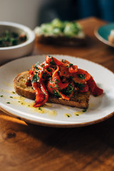 Roasted red peppers on a toasted bread with parsley and olive oil served on a plate