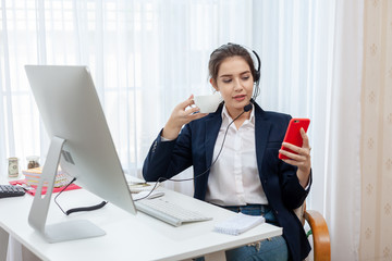 Call center worker. Smiling operator woman holding coffee with headset and mobile phone at office.