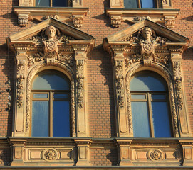 Obraz premium Two ornamental windows on classical house facade. Arched windows on building exterior walls with decorative elements
