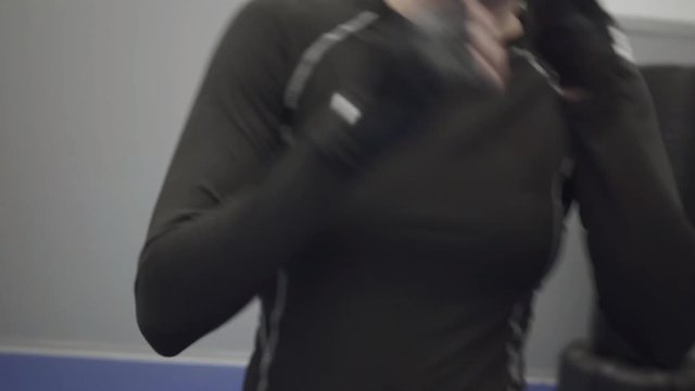Portrait blond woman boxing in the camera in black boxing gloves