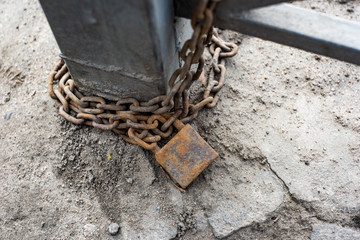 Padlock and chain with corrosion tied around a metal fence