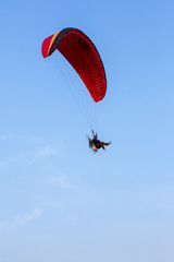 Adventure man active extreme sport pilot flying in sky with paramotor engine glider parachute. Paramotor flying on the sky at sunset. 