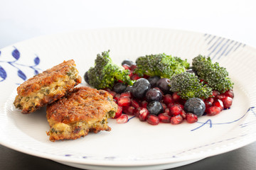 Vegetarian food. Vegetable cutlets from red lentils, onions, parsley and oatmeal. With salad of broccoli, pomegranate seeds and blueberries a variety of nutrients. Close-up with selective focus.
