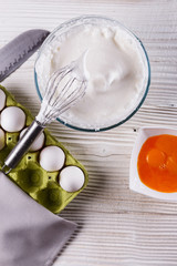 young woman in a gray aprons breaks the eggs