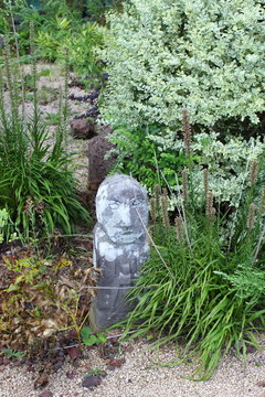 Figure stone grandfather Dolharubang on the flowerbed. The island of Jeju. Korea.