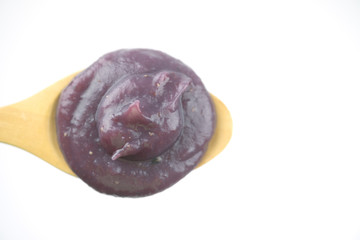 Spoon of purple sweet potato cream soup isolated on white background