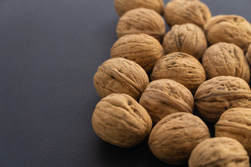 Walnuts in shell lying on black surface, side view. Healthy nuts and seeds background.