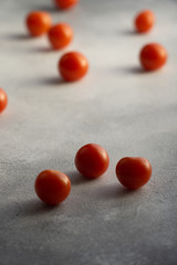 Cherry tomatoes scattered across white textured stone concrete table, with copy space. Ingredients for cooking.