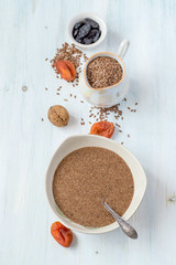 Linseed porridge in a small plate, next to dried apricots, raisins and walnuts. The concept of healthy eating. Selective focus.