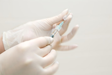 hands in white sterile gloves are preparing a syringe for injection