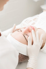 a girl in a white sterile hat is lying on a couch with a beautician and she is doing skin care and massage