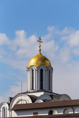 Obraz premium Golden dome of the Orthodox Church with a cross against the blue sky with clouds.