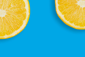Two circles slices of fresh ripe oranges with pulp and peel on blue table on kitchen with copy space for your text. Top view. Concept of prepare of vegetarian food