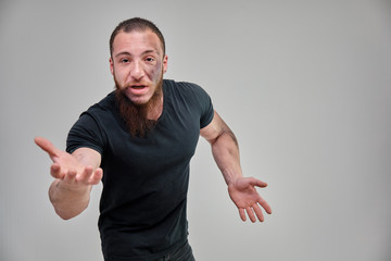 Young brutal man with a beard, bodybuilder in a black t-shirt is standing, posing, talking on a...