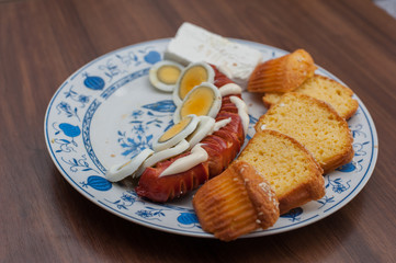 Tasty grilled sausages with cheese and eggs on plate on wooden table