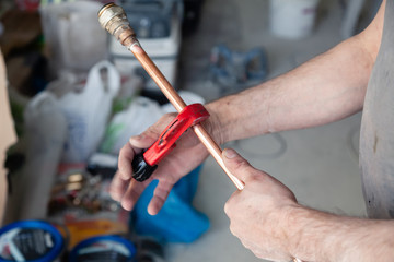 Closeup worker plumber master measures copper pipes with roulette tape, cut pipe with cutter. Concept installation, changing pipeline, repair, leakage, breaking sewage