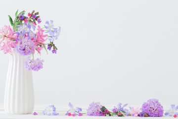 blue and pink flowers in vase on white table