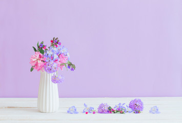 blue and pink flowers in vase on white table