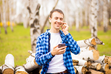 Fototapeta premium Happy man wearing headphones listening to music checking smart phone walking in park