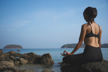 Fototapeta na wymiar Asian Woman practices yoga and meditation on the beach in morning at Phuket,thailand. lifestyle healthy female concept