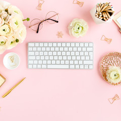 Stylized, pink women's home office desk. Workspace with computer, bouquet ranunculus and roses, clipboard, feminine golden fashion accessories isolated on pink background. Flat lay. Top view.