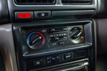 Old Japanese made sports car interior center dashboard with climate control knobs.