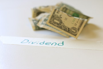 The word dividend next to US 1 dollar bills. Concept of dividend payments and stocks