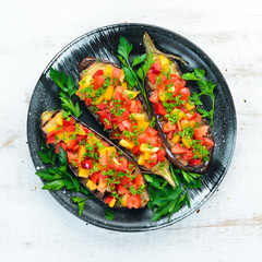 Eggplants baked with vegetables on a black plate. Top view. Free space for your text.