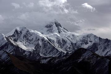 Minya Konka (Mount Gongga, Epic Tibetan Snow Mountain) - Gongga Shan in Sichuan Province, China. View from the west at Yaha Pass, summit shrouded in clouds. Highest Mountain in Sichuan Province China.