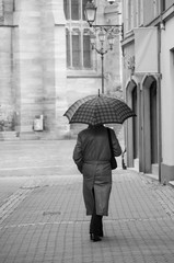portrait of man walking with umbrella in pedestrian street on back view