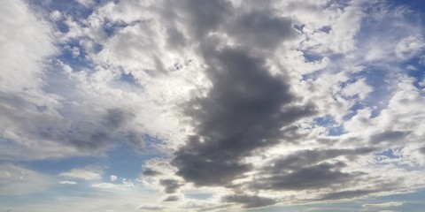 The battle of light and darkness. Light white clouds and dark clouds in the blue sky. Interesting unusual background