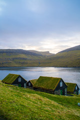 Fototapeta na wymiar Traditional nordic Scandinavian village houses with green grass roof. Iconic scenic view of Faroe Island, Denmark, Europe. Beautiful tourist spot located at Vágar Island. Moody weather scene. 